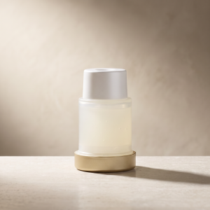 Plated INTENSE Serum Refill cartridge with champagne-gold base on a neutral stone surface